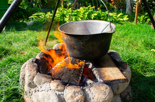 Metal cauldron saucepan in soot for cooking on a campfire hanging over a campfire