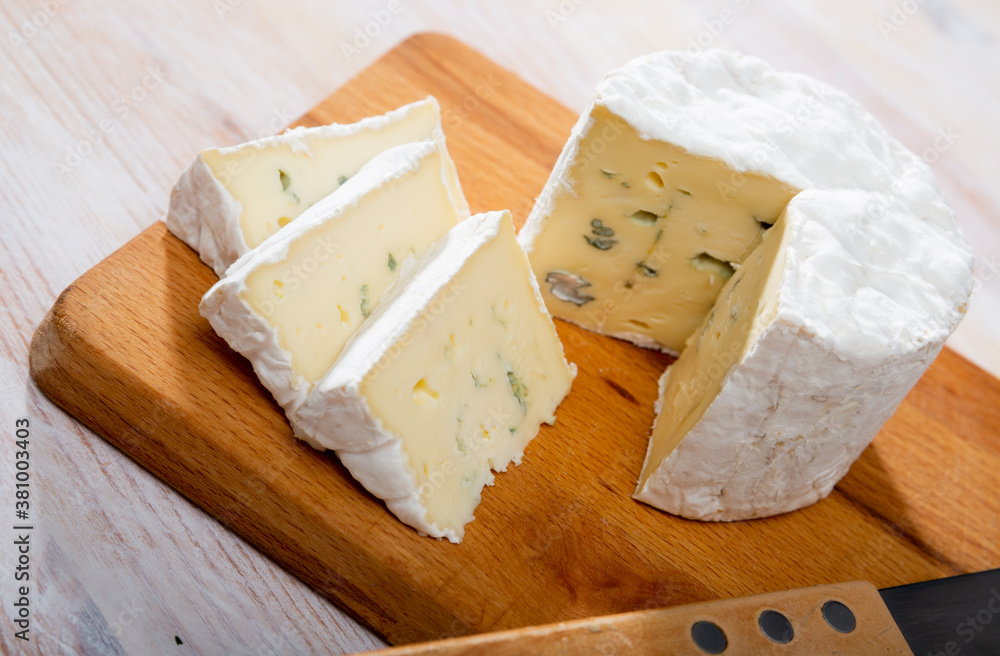 Image of slices of blue cheese with mold at wooden board, nobody
