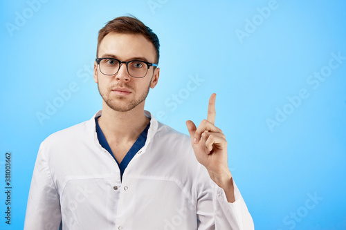 Photos Serious strict doctor in glasses and white coat raised his finger up, makes a re