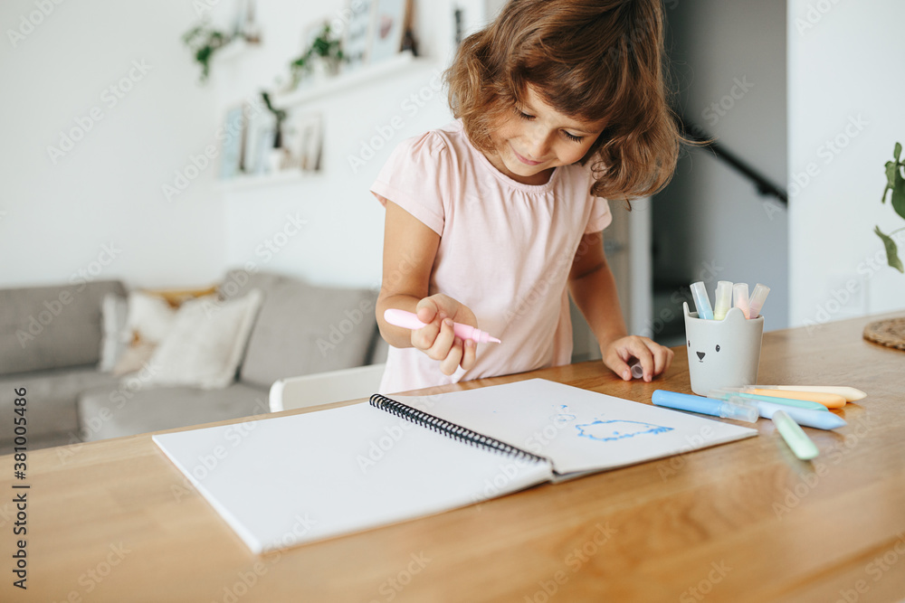 Cute happy little girl, adorable preschooler, 5 years child painting at the table in a white living room at home. Cute happy little girl, adorable preschooler, 5 years child painting at the table in a white living room at home.