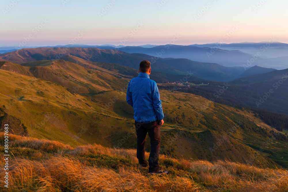 The traveler looks at the houses in the valley of the mountain peak