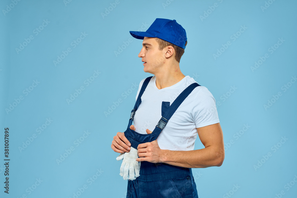 Working man in uniform of gloves loader rendering service blue background Working man in uniform of gloves loader rendering service blue background