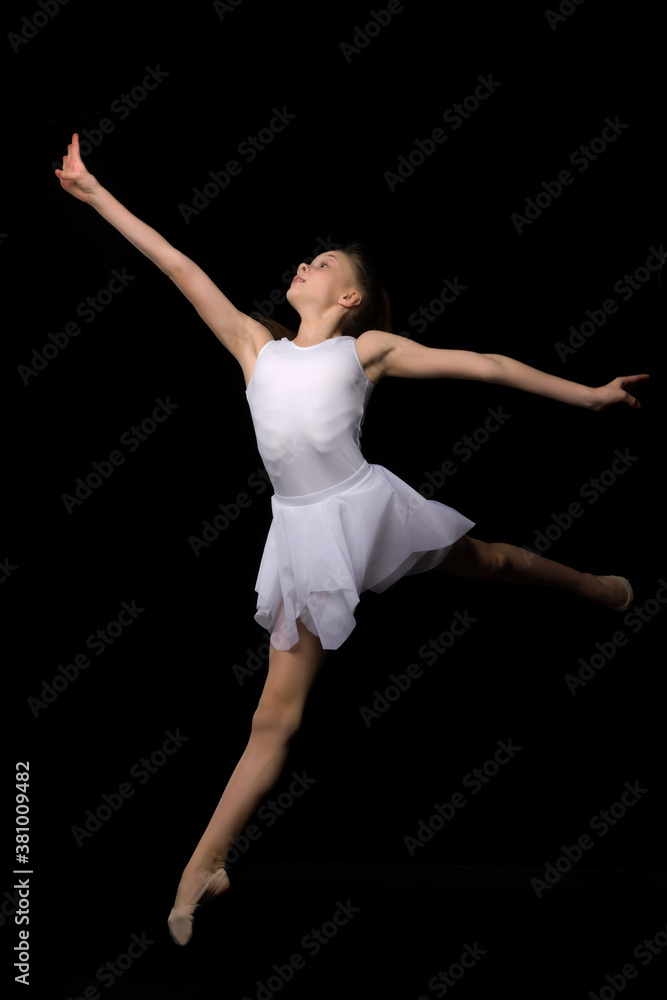 Girl gymnast in the studio on a black background performs gymnastic exercises.