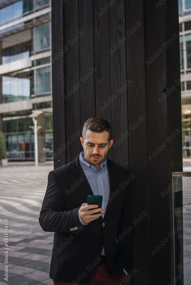 Fototapeta premium Photo of a young and attractive business man checking his phone. Wearing smart casual clothes. Entrepeneur style
