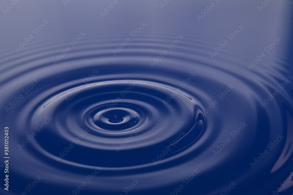 Conceptual blue liquid falling in water background with ripples and waves Conceptual blue liquid falling in water background with ripples and waves