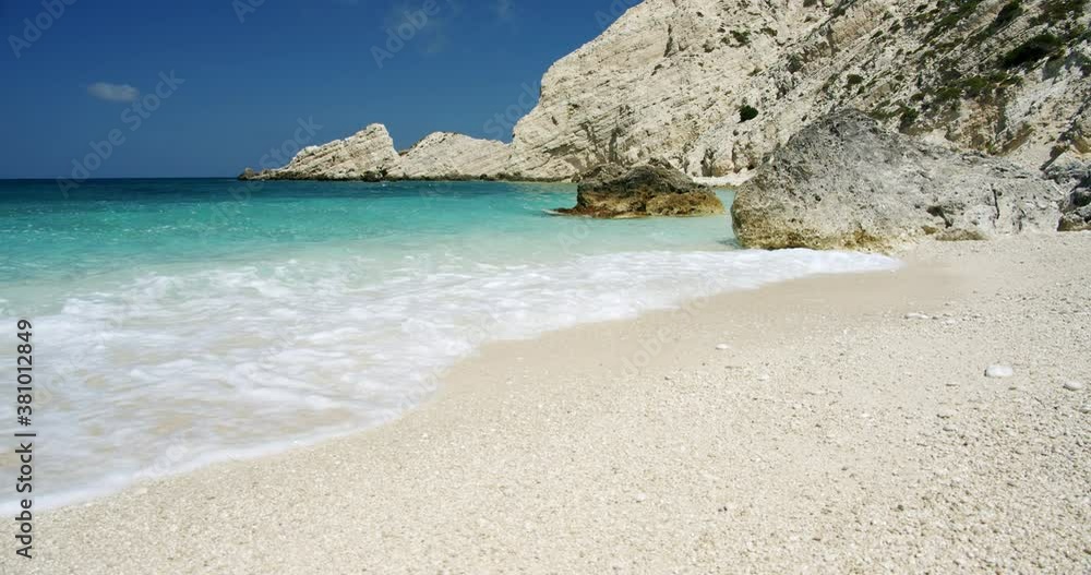 Clear sea waves splashing on peaceful white beach with pebbles, seascape with rocks in background. Clear sea waves splashing on peaceful white beach with pebbles, seascape with rocks in background.