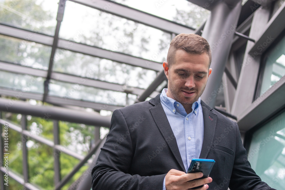 Photo of a young and attractive business man wearing smart casual clothes checking his phone before a meeting. Photo of a young and attractive business man wearing smart casual clothes checking his phone before a meeting.