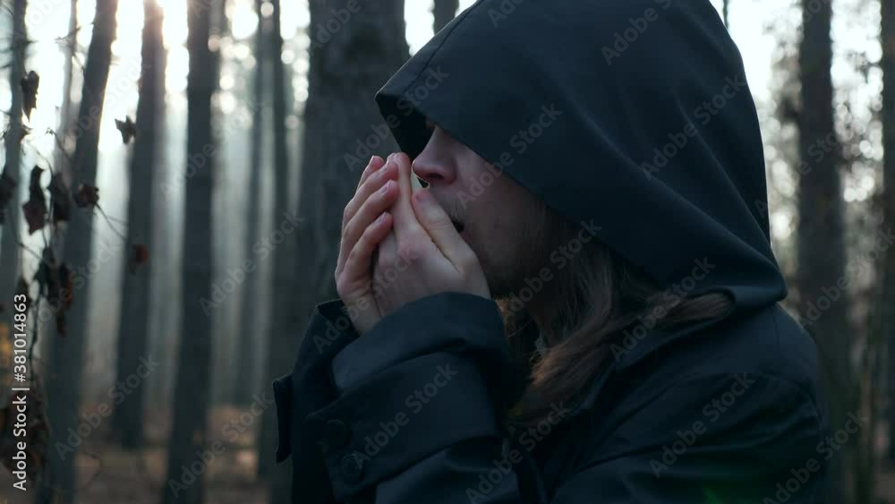 Man Warms Hands. Wanderer in Black Cloak Cowl Traveling in Misty Forest. Autumn Morning. 2x Slow motion 60 FPS Man Warms Hands. Wanderer in Black Cloak Cowl Traveling in Misty Forest. Autumn Morning. 2x Slow motion 60 FPS