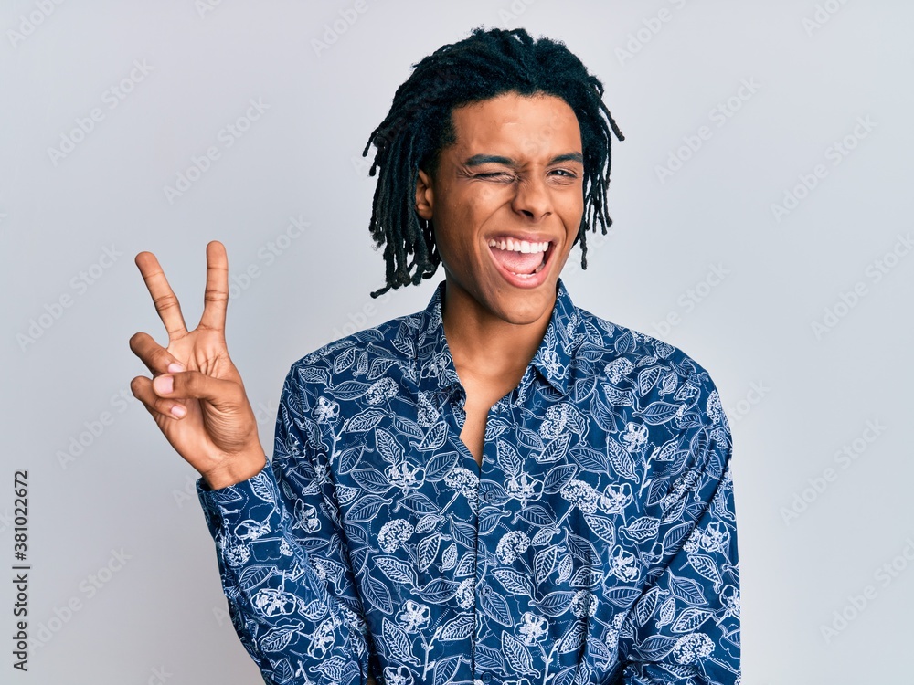 Young african american man wearing 80s style shirt smiling with happy face winking at the camera doing victory sign. number two. Young african american man wearing 80s style shirt smiling with happy face winking at the camera doing victory sign. number two.