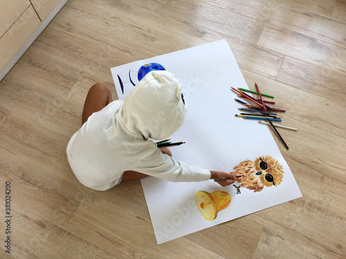 a child sits on the floor and draws a wall paper for school with an owl in pencil
