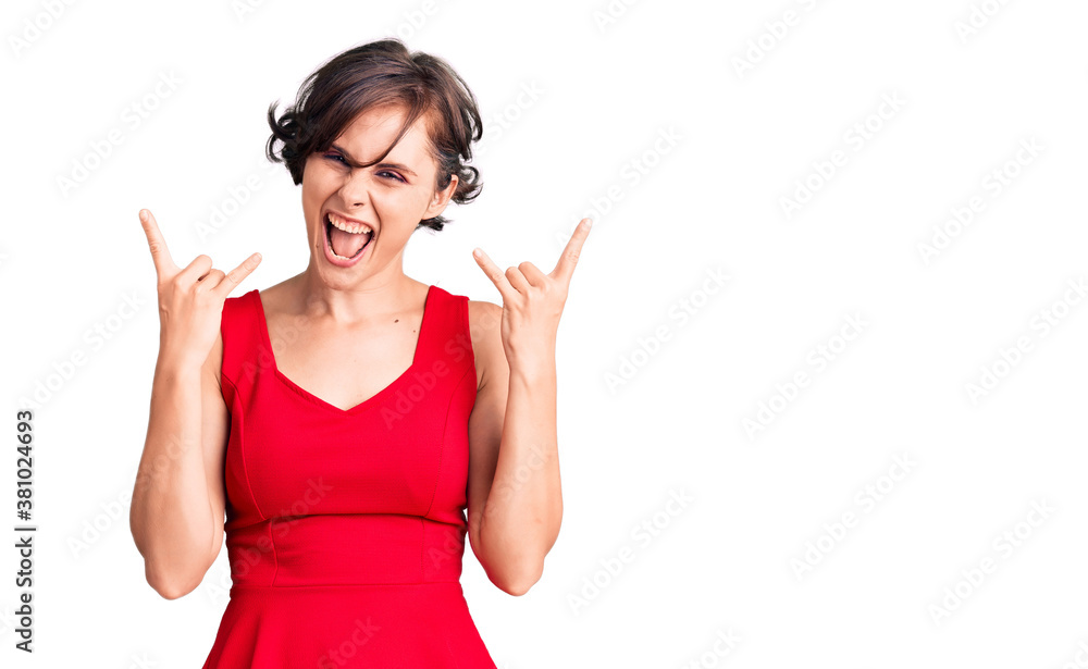 Beautiful young woman with short hair wearing casual style with sleeveless shirt shouting with crazy expression doing rock symbol with hands up. music star. heavy music concept. Beautiful young woman with short hair wearing casual style with sleeveless shirt shouting with crazy expression doing rock symbol with hands up. music star. heavy music concept.