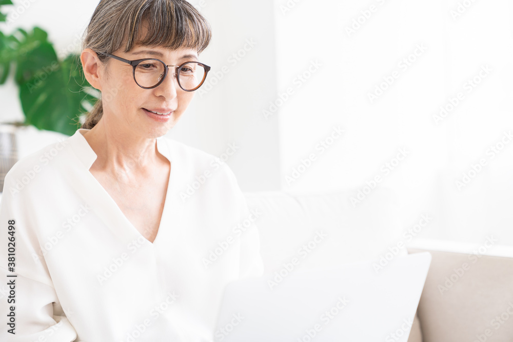 部屋でラップトップコンピューターを見るシニア女性 部屋でラップトップコンピューターを見るシニア女性