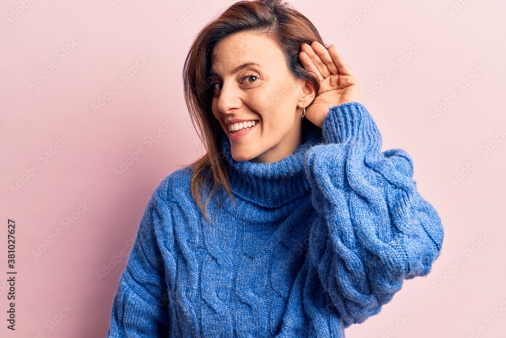 Young beautiful woman wearing winter sweater smiling with hand over ear listening and hearing to rumor or gossip. deafness concept. Young beautiful woman wearing winter sweater smiling with hand over ear listening and hearing to rumor or gossip. deafness concept.
