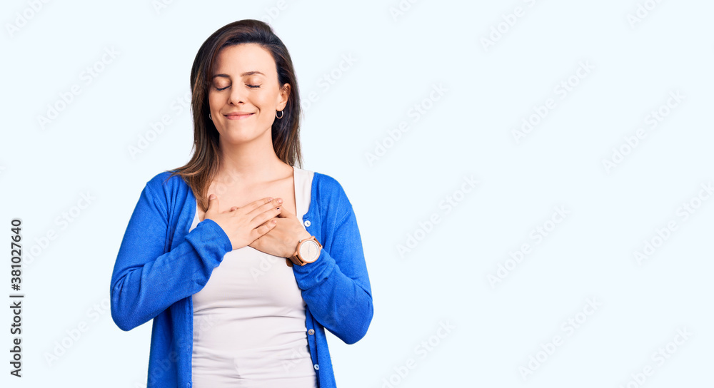 Young beautiful woman wearing casual clothes smiling with hands on chest with closed eyes and grateful gesture on face. health concept. Young beautiful woman wearing casual clothes smiling with hands on chest with closed eyes and grateful gesture on face. health concept.