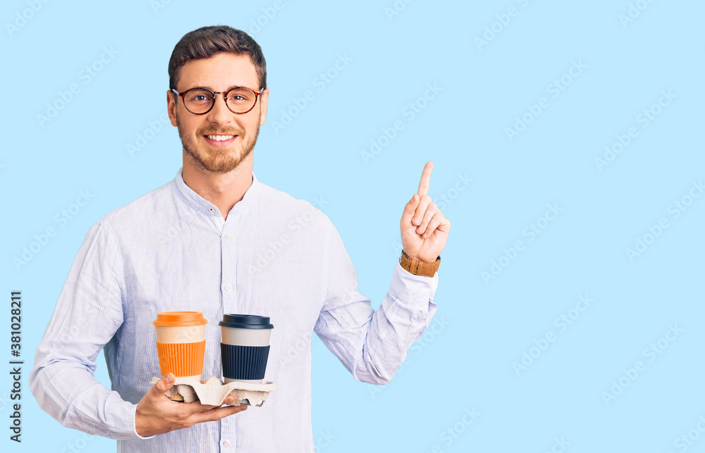 Handsome young man with bear holding takeaway cup of coffee surprised with an idea or question pointing finger with happy face, number one Handsome young man with bear holding takeaway cup of coffee surprised with an idea or question pointing finger with happy face, number one