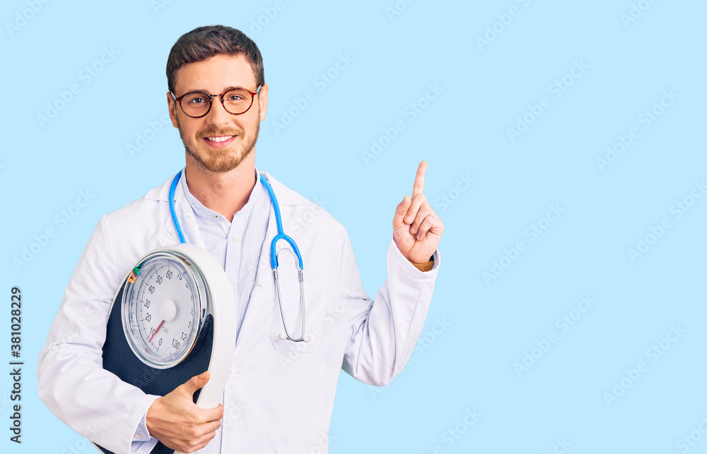 Handsome young man with bear as nutritionist doctor holding weighing machine surprised with an idea or question pointing finger with happy face, number one Handsome young man with bear as nutritionist doctor holding weighing machine surprised with an idea or question pointing finger with happy face, number one