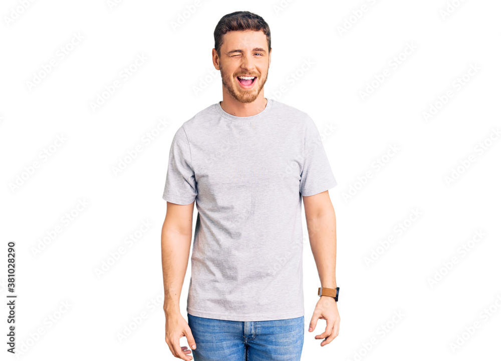 Handsome young man with bear wearing casual tshirt winking looking at the camera with sexy expression, cheerful and happy face. Handsome young man with bear wearing casual tshirt winking looking at the camera with sexy expression, cheerful and happy face.