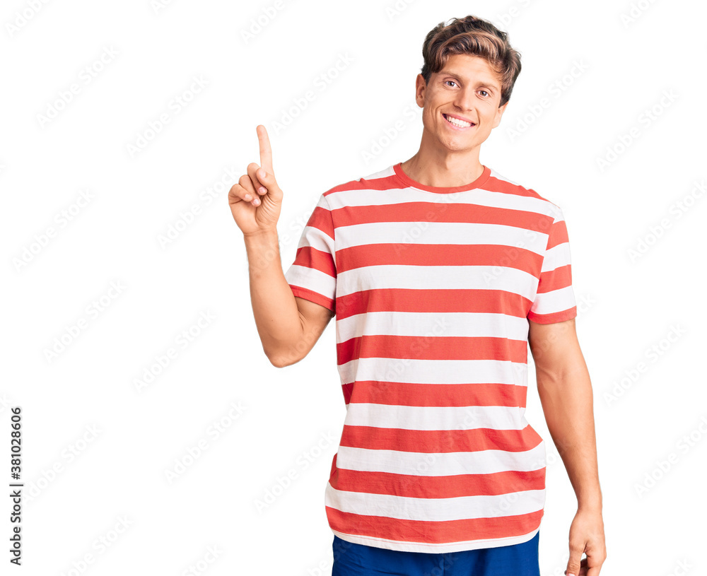 Young handsome man wearing casual clothes showing and pointing up with finger number one while smiling confident and happy. Young handsome man wearing casual clothes showing and pointing up with finger number one while smiling confident and happy.