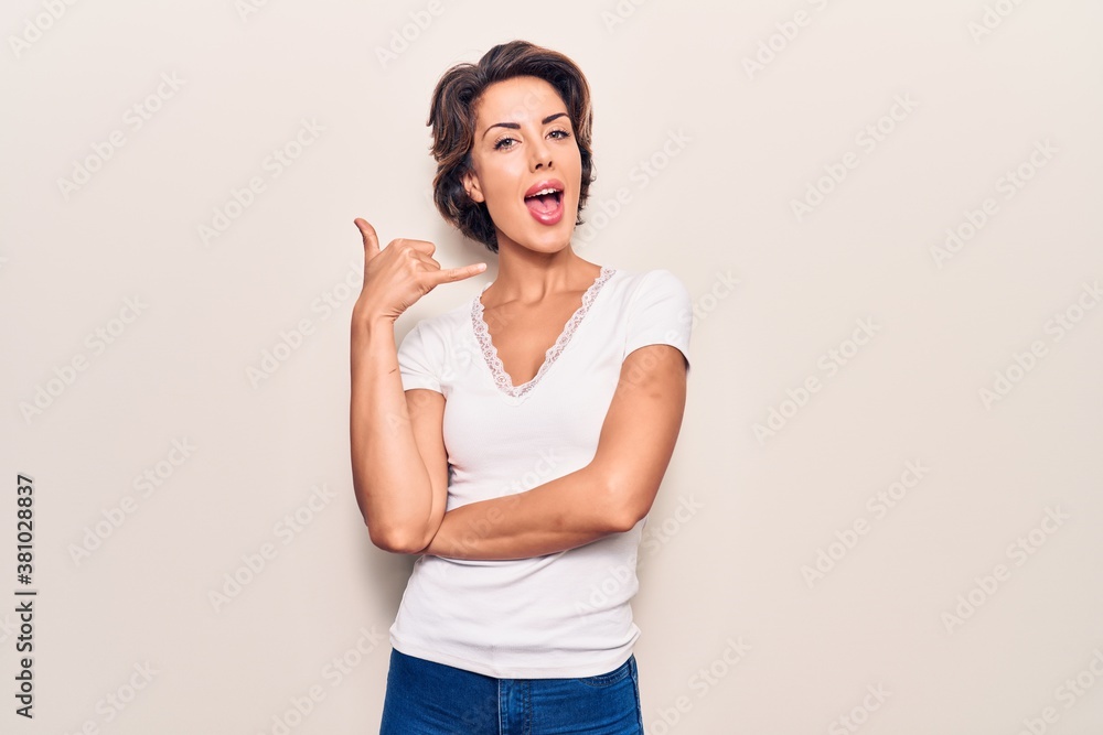 Young beautiful woman wearing casual clothes smiling doing phone gesture with hand and fingers like talking on the telephone. communicating concepts. Young beautiful woman wearing casual clothes smiling doing phone gesture with hand and fingers like talking on the telephone. communicating concepts.