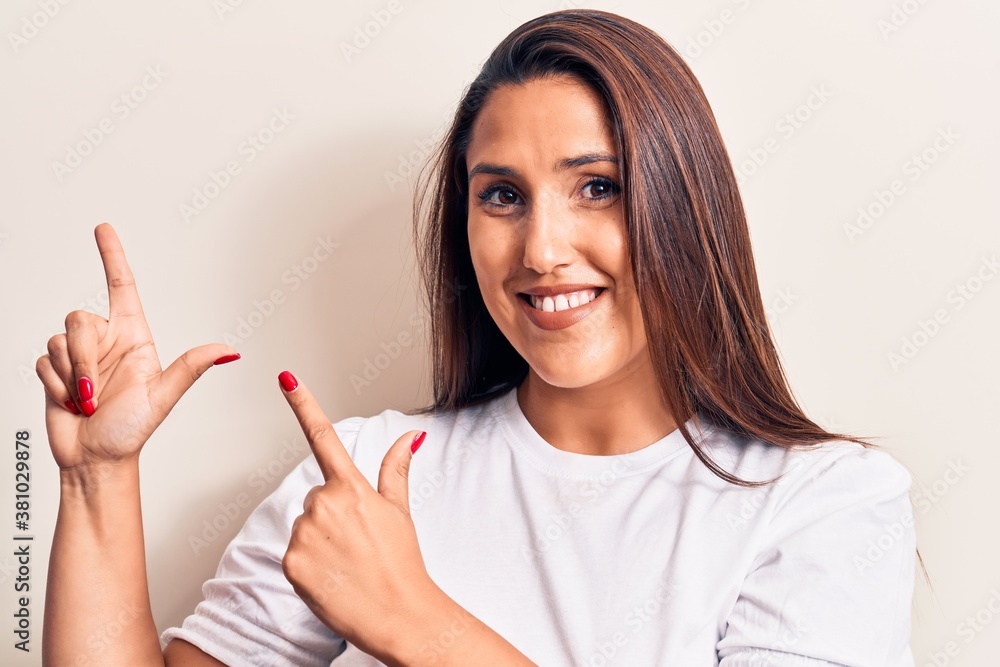 Young beautiful brunette woman wearing casual t-shirt smiling and looking at the camera pointing with two hands and fingers to the side. Young beautiful brunette woman wearing casual t-shirt smiling and looking at the camera pointing with two hands and fingers to the side.