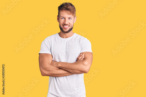 Young caucasian man wearing casual white tshirt happy face smiling with crossed arms looking at the camera. positive person.