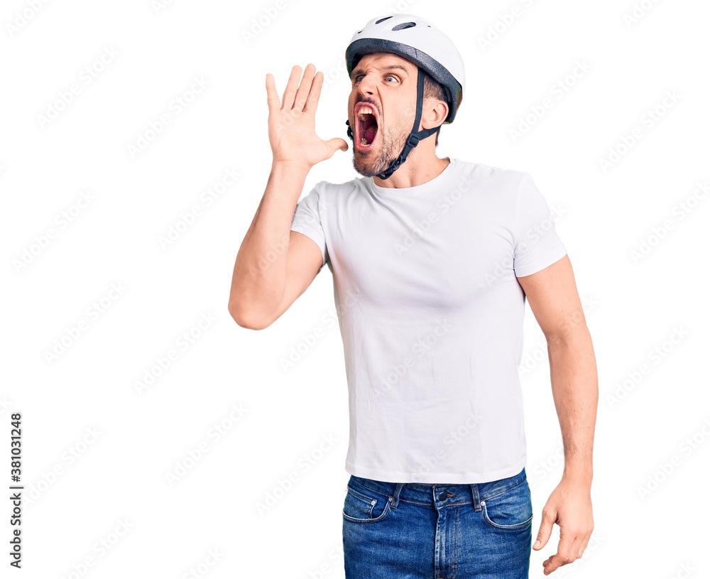 Young handsome man wearing bike helmet shouting and screaming loud to side with hand on mouth. communication concept. Young handsome man wearing bike helmet shouting and screaming loud to side with hand on mouth. communication concept.