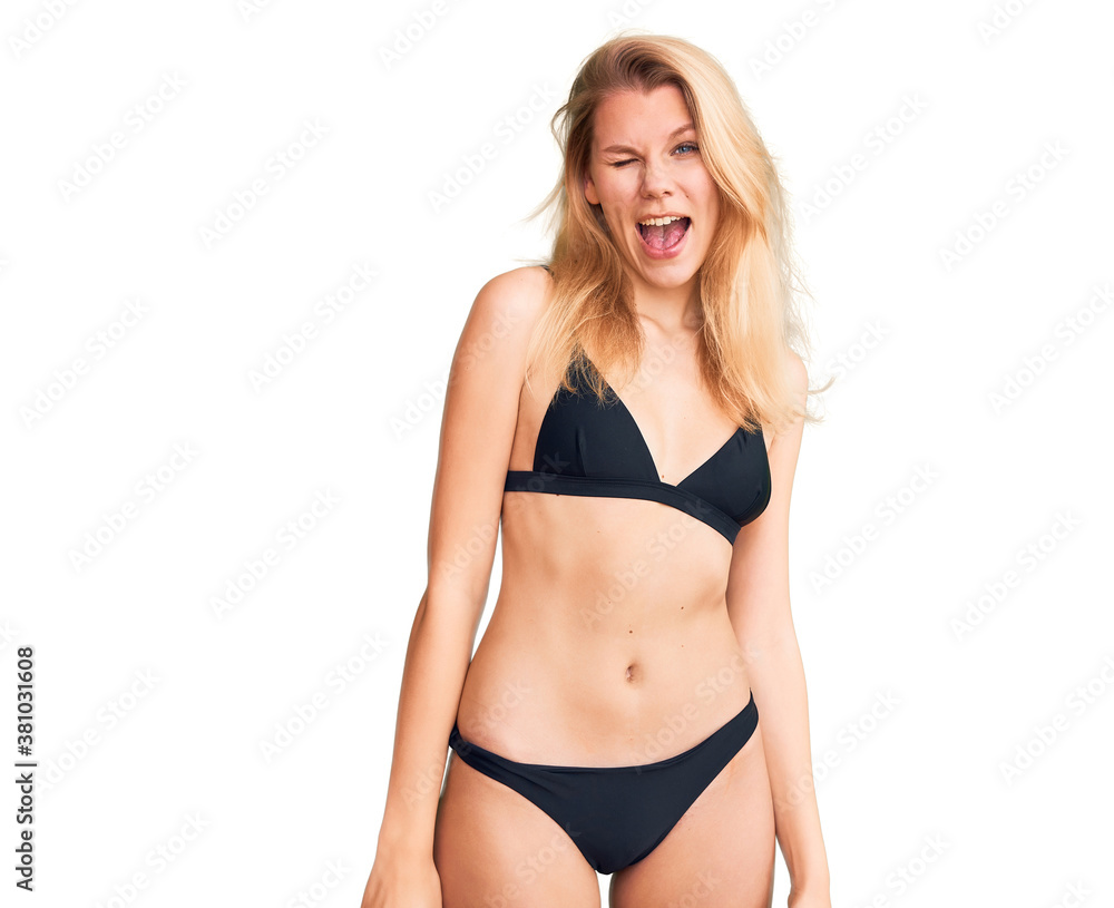 Young beautiful blonde woman wearing bikini winking looking at the camera with sexy expression, cheerful and happy face. Young beautiful blonde woman wearing bikini winking looking at the camera with sexy expression, cheerful and happy face.