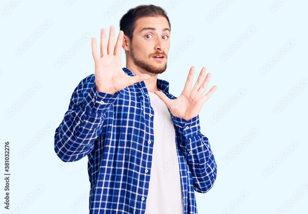 Young handsome caucasian man wearing casual clothes afraid and terrified with fear expression stop gesture with hands, shouting in shock. panic concept. Young handsome caucasian man wearing casual clothes afraid and terrified with fear expression stop gesture with hands, shouting in shock. panic concept.