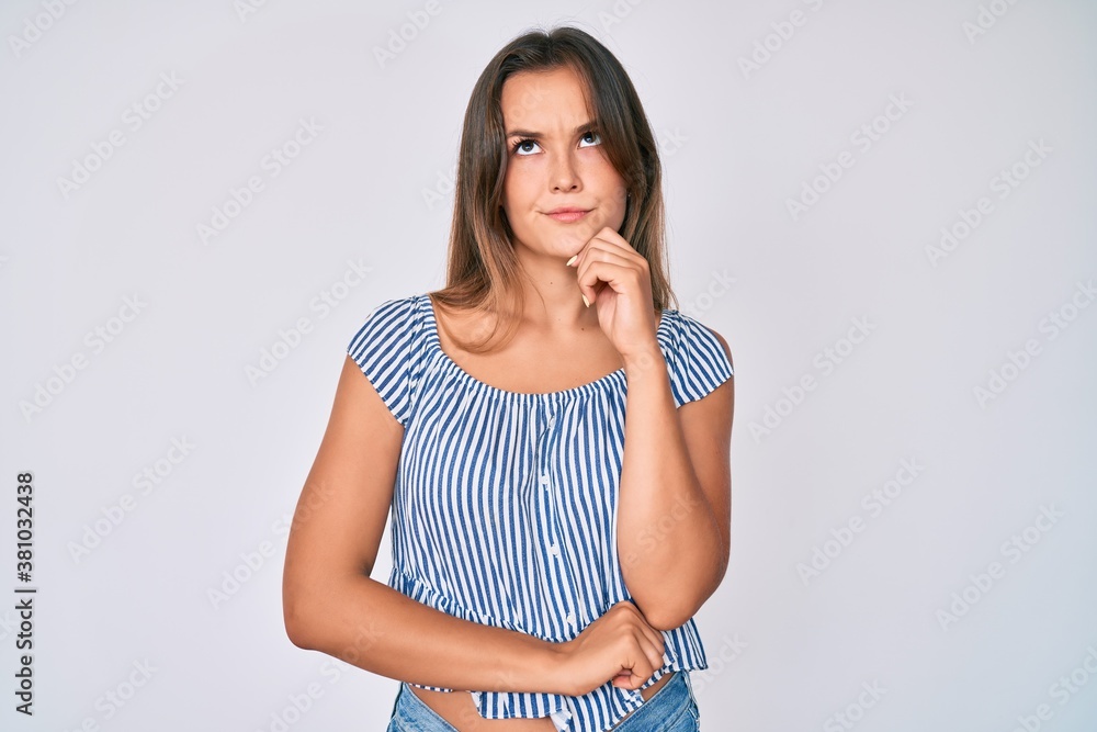 Beautiful caucasian woman wearing casual striped shirt thinking concentrated about doubt with finger on chin and looking up wondering Beautiful caucasian woman wearing casual striped shirt thinking concentrated about doubt with finger on chin and looking up wondering