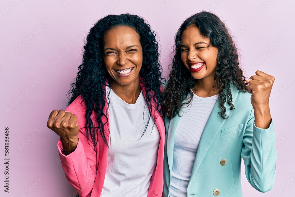 African american mother and daughter wearing business style very happy and excited doing winner gesture with arms raised, smiling and screaming for success. celebration concept. African american mother and daughter wearing business style very happy and excited doing winner gesture with arms raised, smiling and screaming for success. celebration concept.
