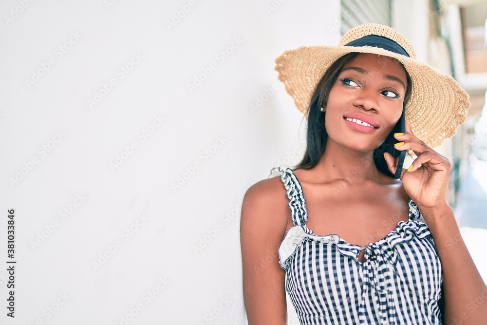 Young african american woman on vacation talking on the smartphone leaning on the wall at street of city Young african american woman on vacation talking on the smartphone leaning on the wall at street of city