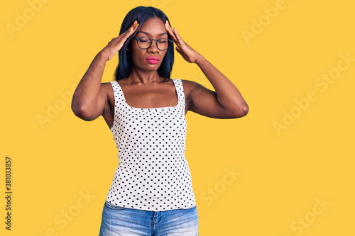 Young african american woman wearing casual clothes and glasses suffering from headache desperate and stressed because pain and migraine. hands on head.