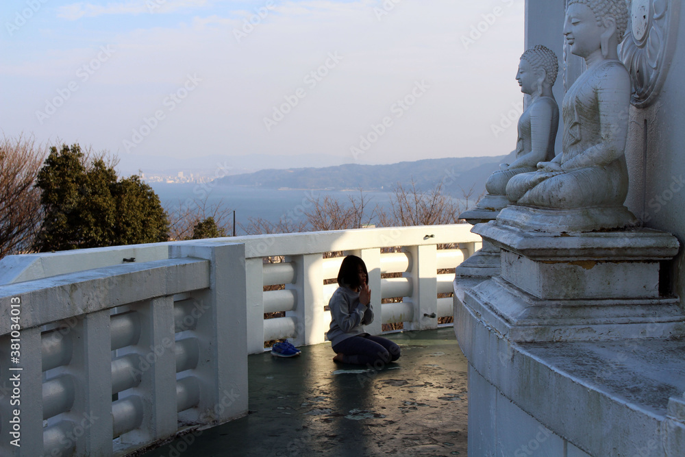 Φωτογραφία Girl praying in front of Buddha statue at Myohoji Temple Pagoda of Beppu