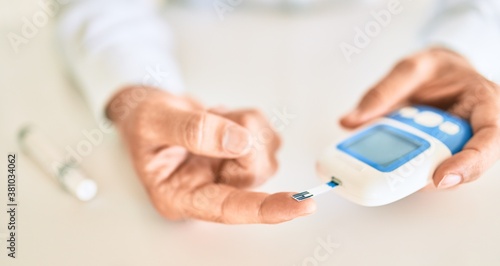 Obraz na płótnie Close up of man with diabetes using insuline glucometer with blood from the fing