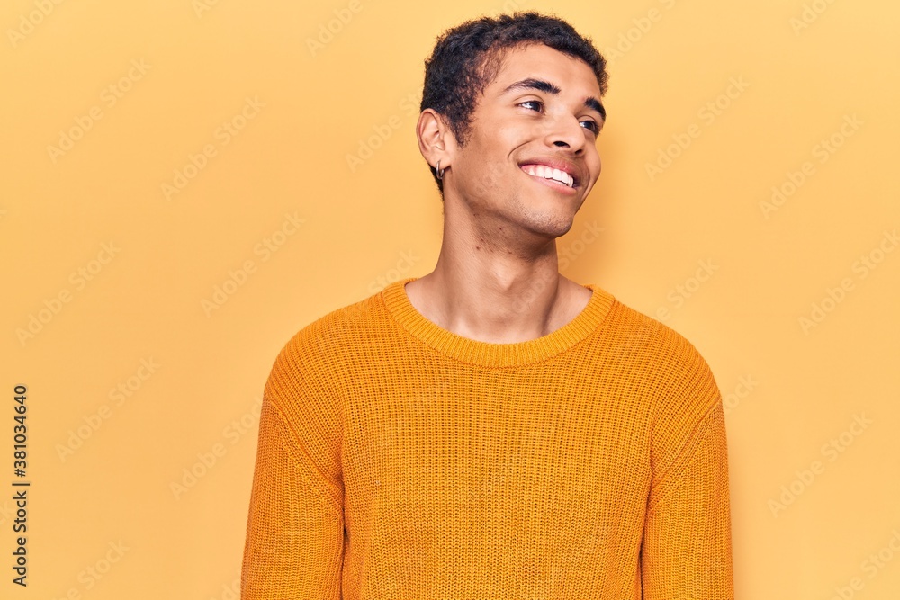 Young african amercian man wearing casual clothes looking away to side with smile on face, natural expression. laughing confident. Young african amercian man wearing casual clothes looking away to side with smile on face, natural expression. laughing confident.