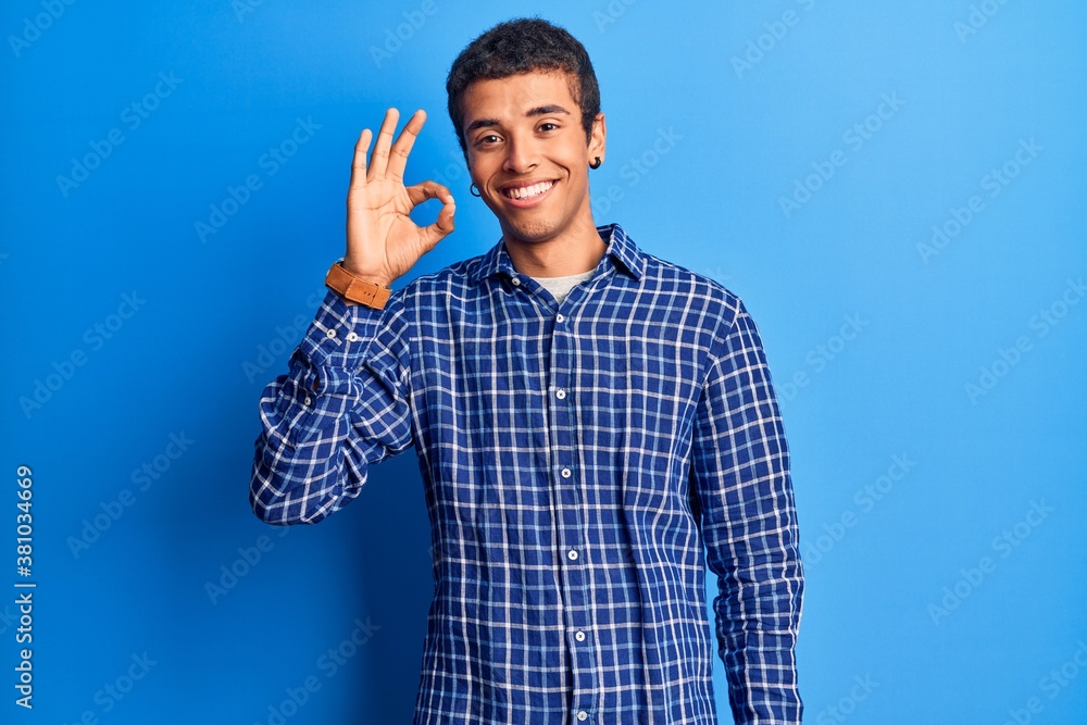 Young african amercian man wearing casual clothes smiling positive doing ok sign with hand and fingers. successful expression. Young african amercian man wearing casual clothes smiling positive doing ok sign with hand and fingers. successful expression.