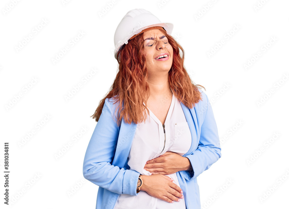 Young latin woman wearing architect hardhat with hand on stomach because nausea, painful disease feeling unwell. ache concept. Young latin woman wearing architect hardhat with hand on stomach because nausea, painful disease feeling unwell. ache concept.