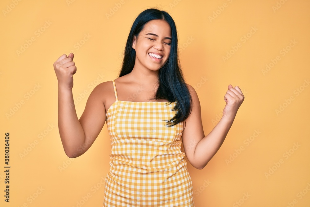 Young beautiful asian girl wearing casual clothes very happy and excited doing winner gesture with arms raised, smiling and screaming for success. celebration concept. Young beautiful asian girl wearing casual clothes very happy and excited doing winner gesture with arms raised, smiling and screaming for success. celebration concept.