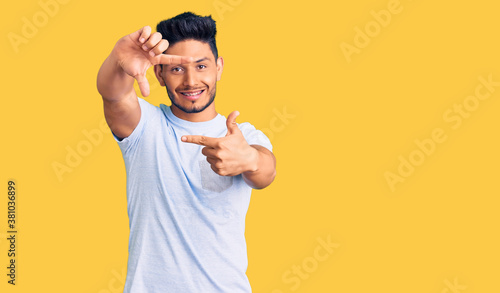 Handsome latin american young man wearing casual clothes smiling making frame with hands and fingers with happy face. creativity and photography concept.