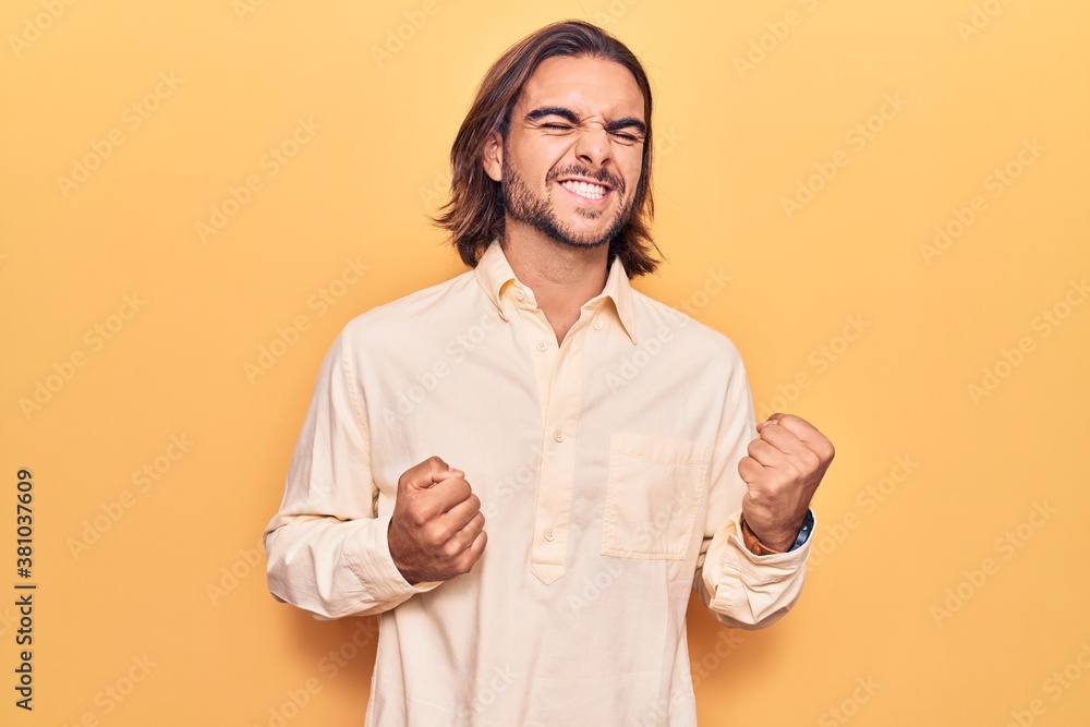 Young handsome man wearing business clothes excited for success with arms raised and eyes closed celebrating victory smiling. winner concept. Young handsome man wearing business clothes excited for success with arms raised and eyes closed celebrating victory smiling. winner concept.