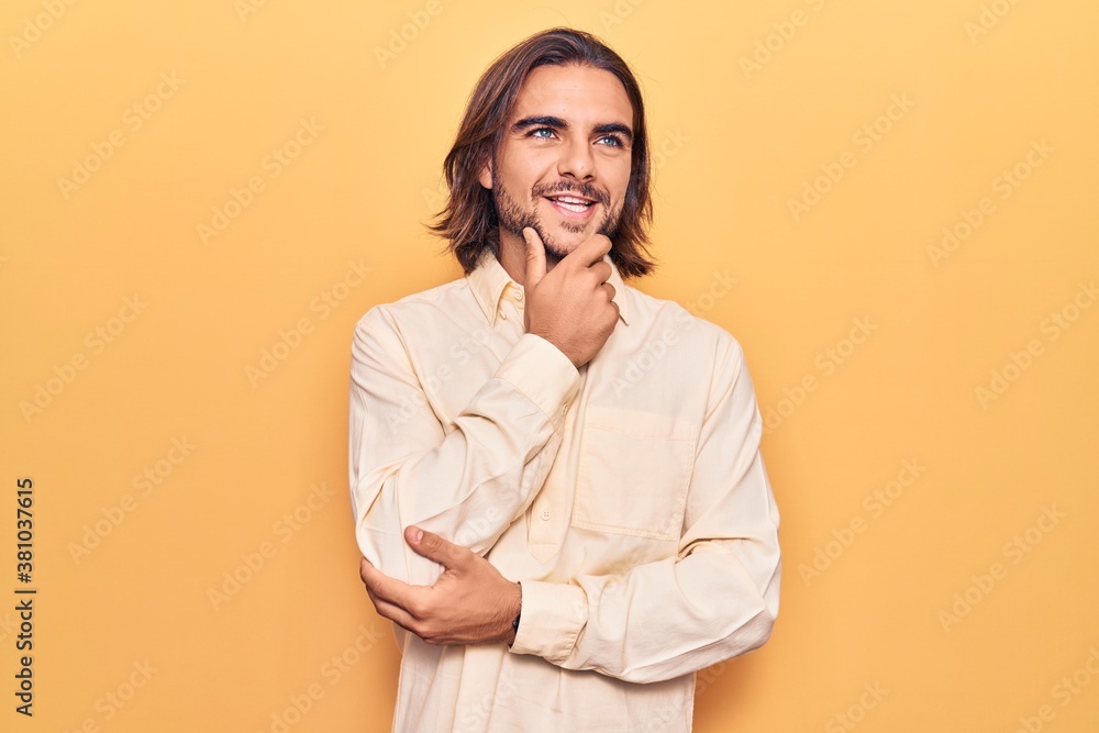 Young handsome man wearing business clothes with hand on chin thinking about question, pensive expression. smiling with thoughtful face. doubt concept. Young handsome man wearing business clothes with hand on chin thinking about question, pensive expression. smiling with thoughtful face. doubt concept.