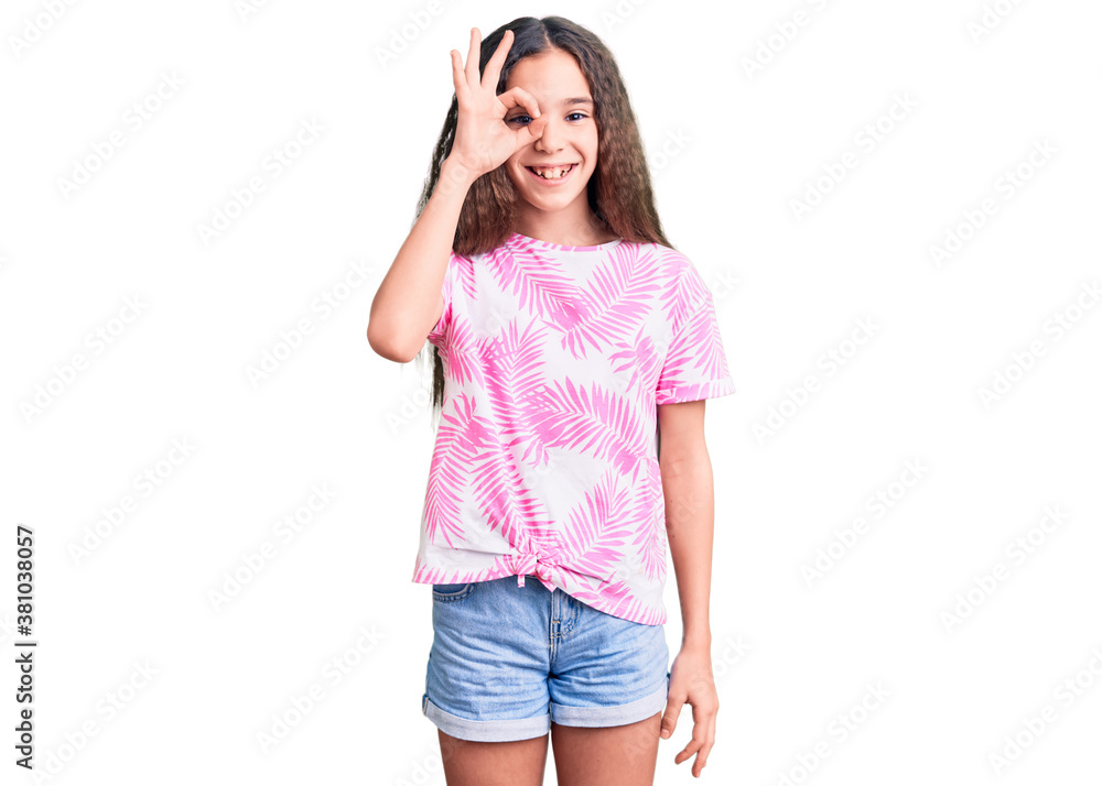 Cute hispanic child girl wearing casual clothes doing ok gesture with hand smiling, eye looking through fingers with happy face. Cute hispanic child girl wearing casual clothes doing ok gesture with hand smiling, eye looking through fingers with happy face.