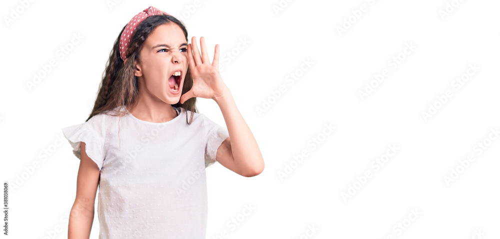 Cute hispanic child girl wearing casual white tshirt shouting and screaming loud to side with hand on mouth. communication concept. Cute hispanic child girl wearing casual white tshirt shouting and screaming loud to side with hand on mouth. communication concept.