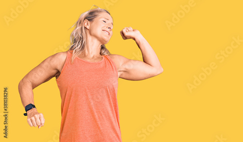 Middle age fit blonde woman wearing casual summer clothes and sunglasses stretching back, tired and relaxed, sleepy and yawning for early morning © Krakenimages.com