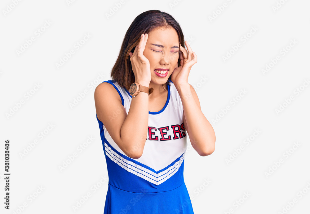 Young beautiful chinese girl wearing cheerleader uniform with hand on head, headache because stress. suffering migraine. Young beautiful chinese girl wearing cheerleader uniform with hand on head, headache because stress. suffering migraine.