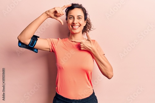 Young beautiful hispanic woman wearing sportswear using smartphone smiling making frame with hands and fingers with happy face. creativity and photography concept. © Krakenimages.com