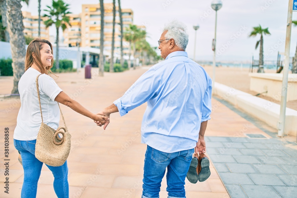 Middle age hispanic couple smiling happy walking at the promenade