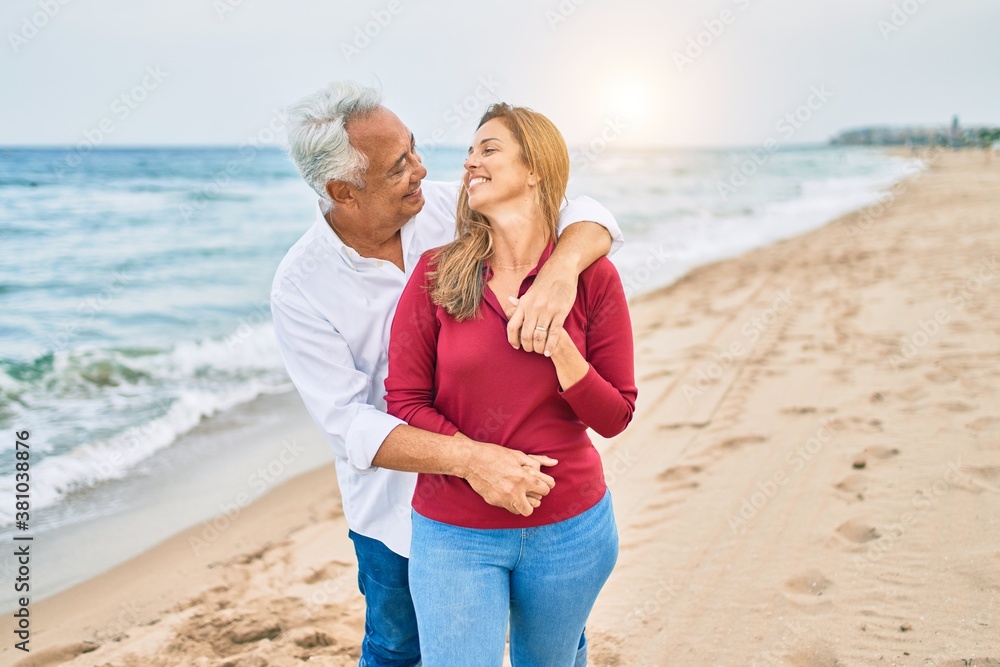 Middle age hispanic couple smiling happy and hugging walking at the beach Middle age hispanic couple smiling happy and hugging walking at the beach