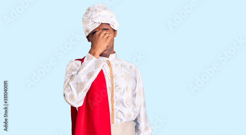 African handsome man wearing tradition sherwani saree clothes tired rubbing nose and eyes feeling fatigue and headache. stress and frustration concept. photo