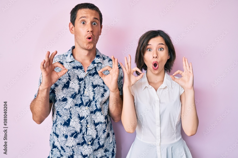 Beautiful couple wearing casual clothes looking surprised and shocked doing ok approval symbol with fingers. crazy expression Beautiful couple wearing casual clothes looking surprised and shocked doing ok approval symbol with fingers. crazy expression